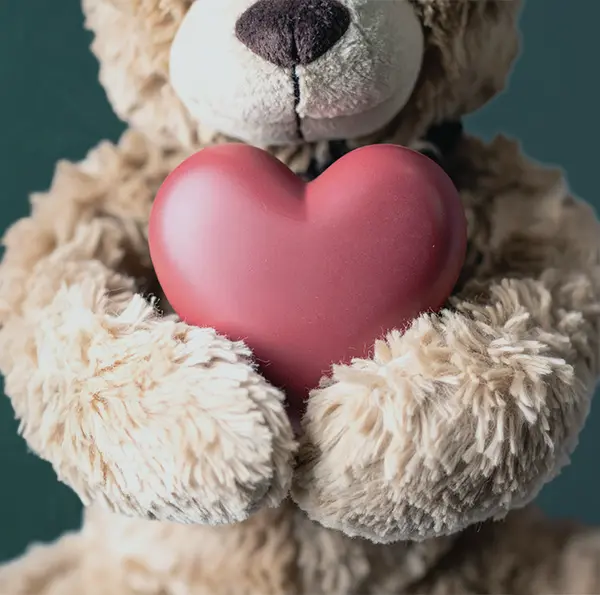 a teddybear holding a heart, in a bright, sunny clinic